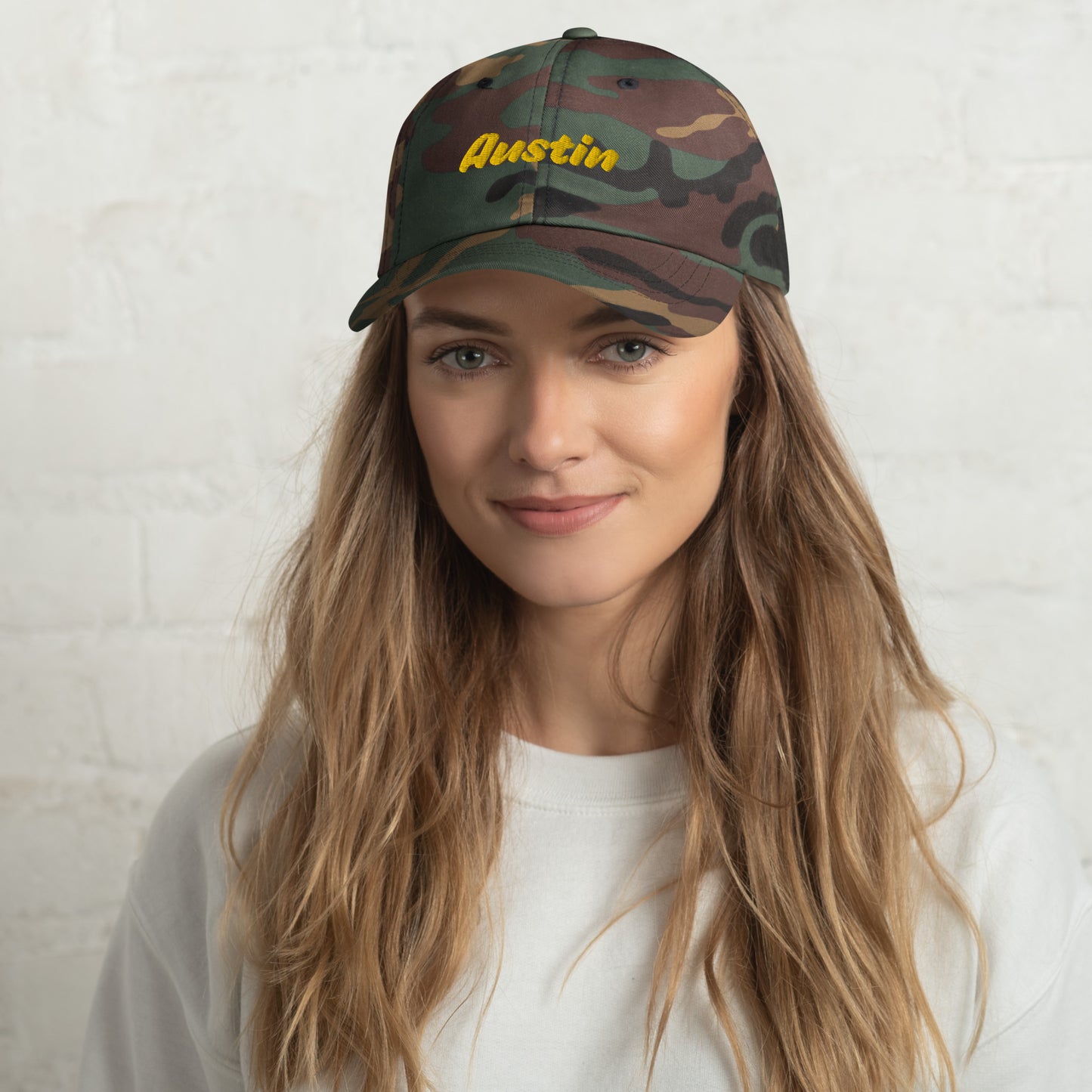 Austin city editions with “Austin” type in yellow embroidery on camo casual dad hat front view on female model