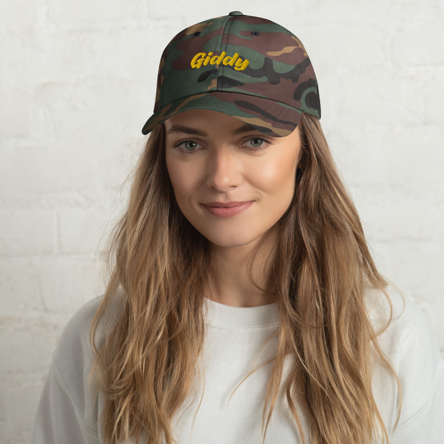 Austin city editions with “Giddy” type in yellow embroidery on camo casual dad hat front view on female model