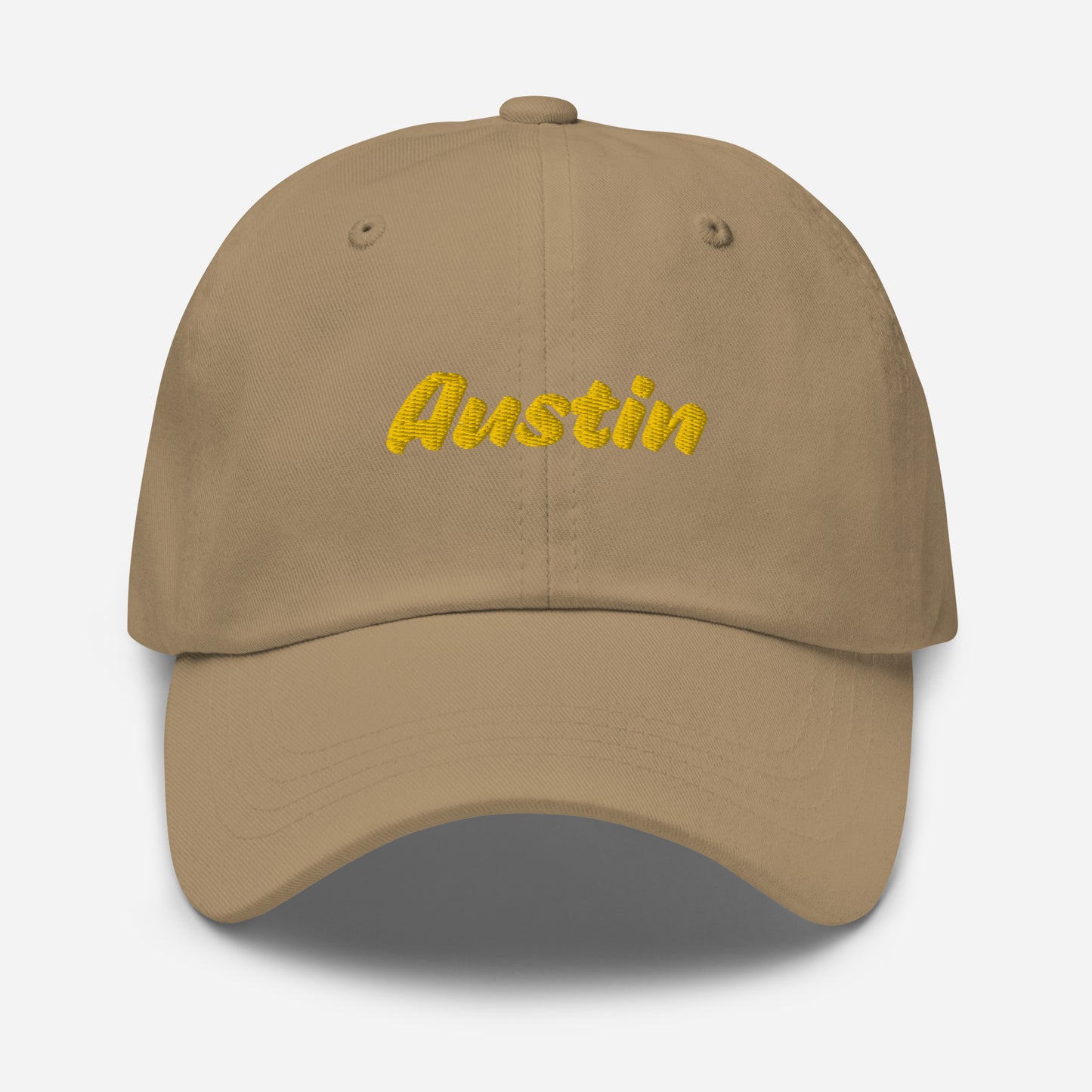 Austin city editions with “Austin” type in yellow embroidery on khaki casual dad hat front view on white background