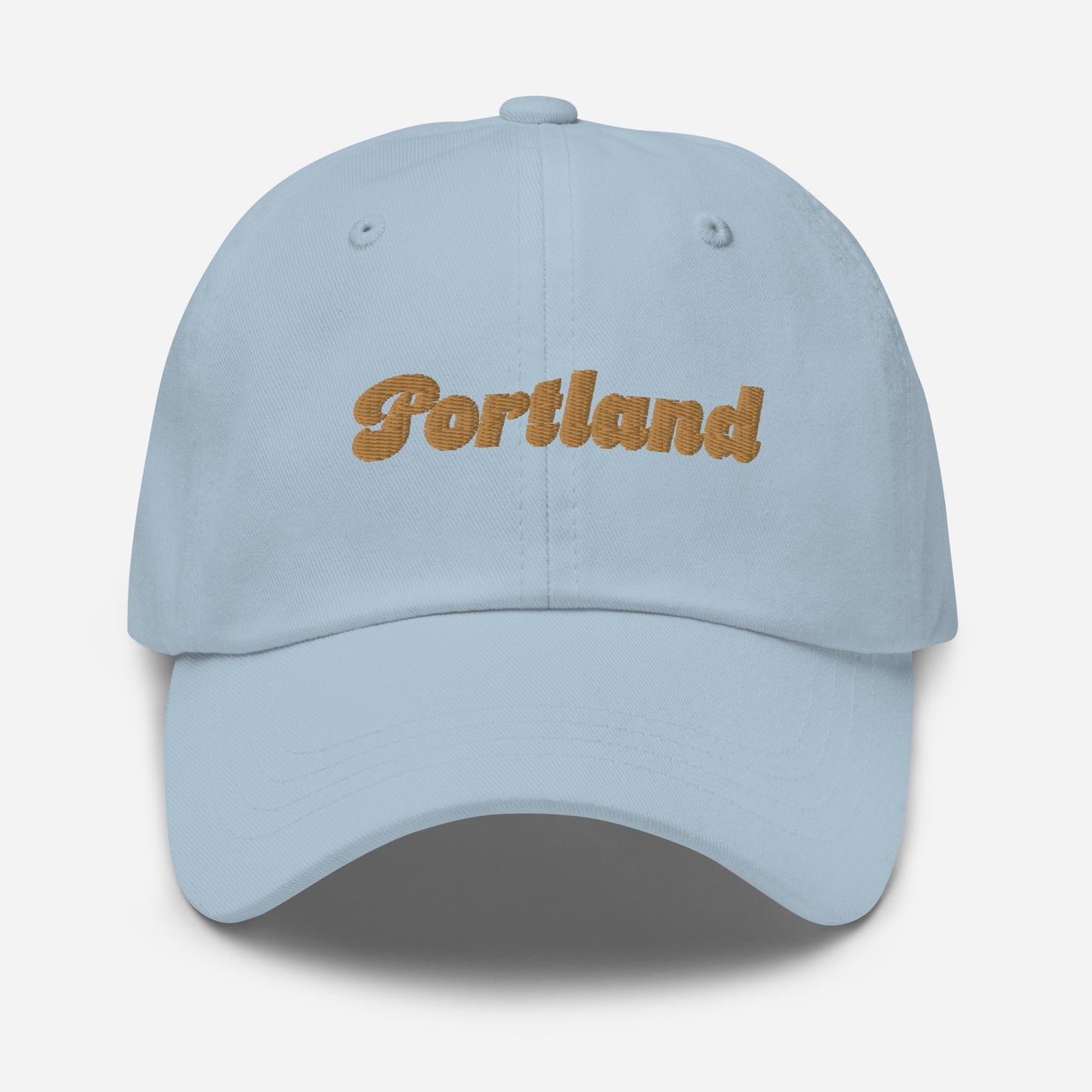 Portland city editions with “Portland” type in gold embroidery on light blue casual dad hat front view on white background