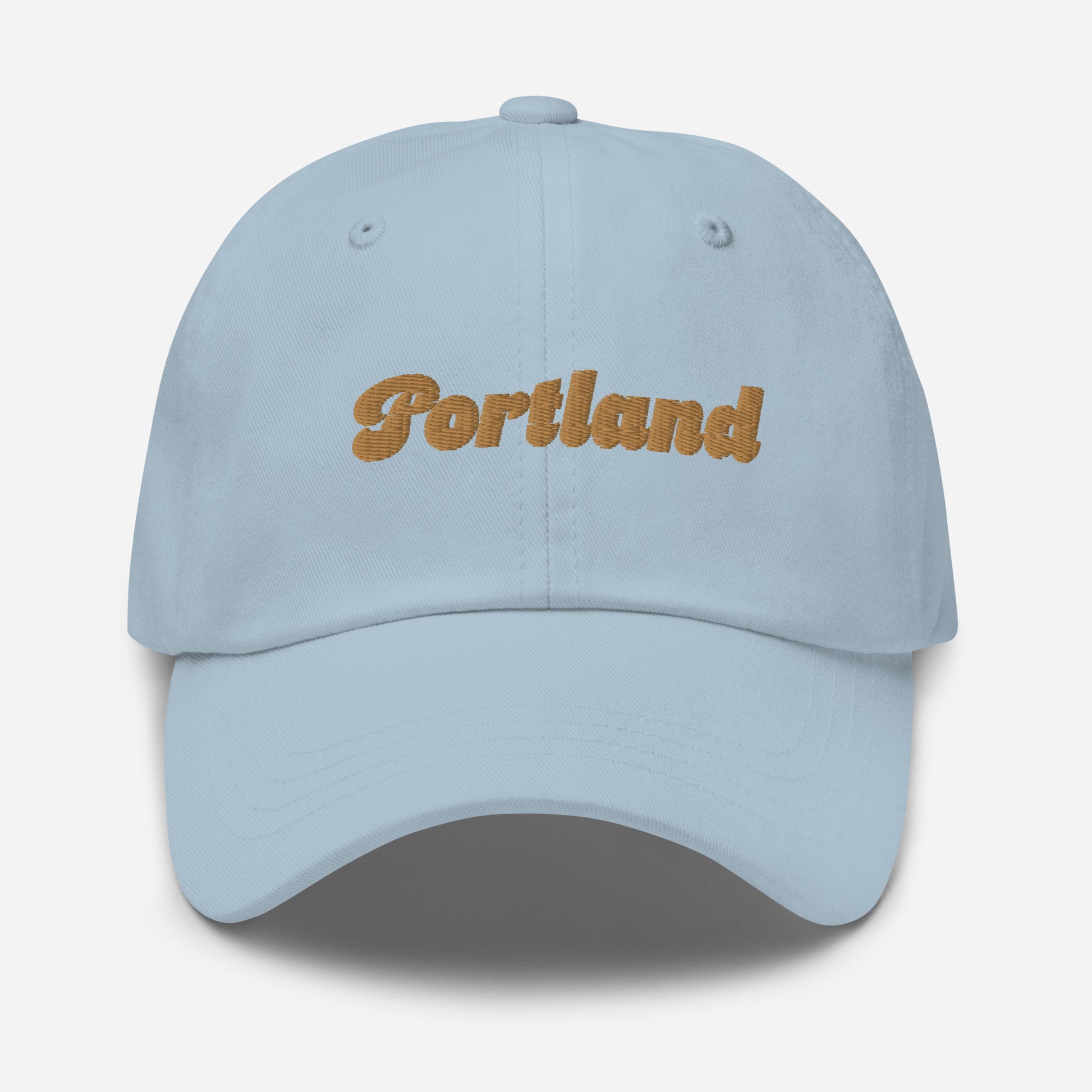 Portland city editions with “Portland” type in gold embroidery on light blue casual dad hat front view on white background