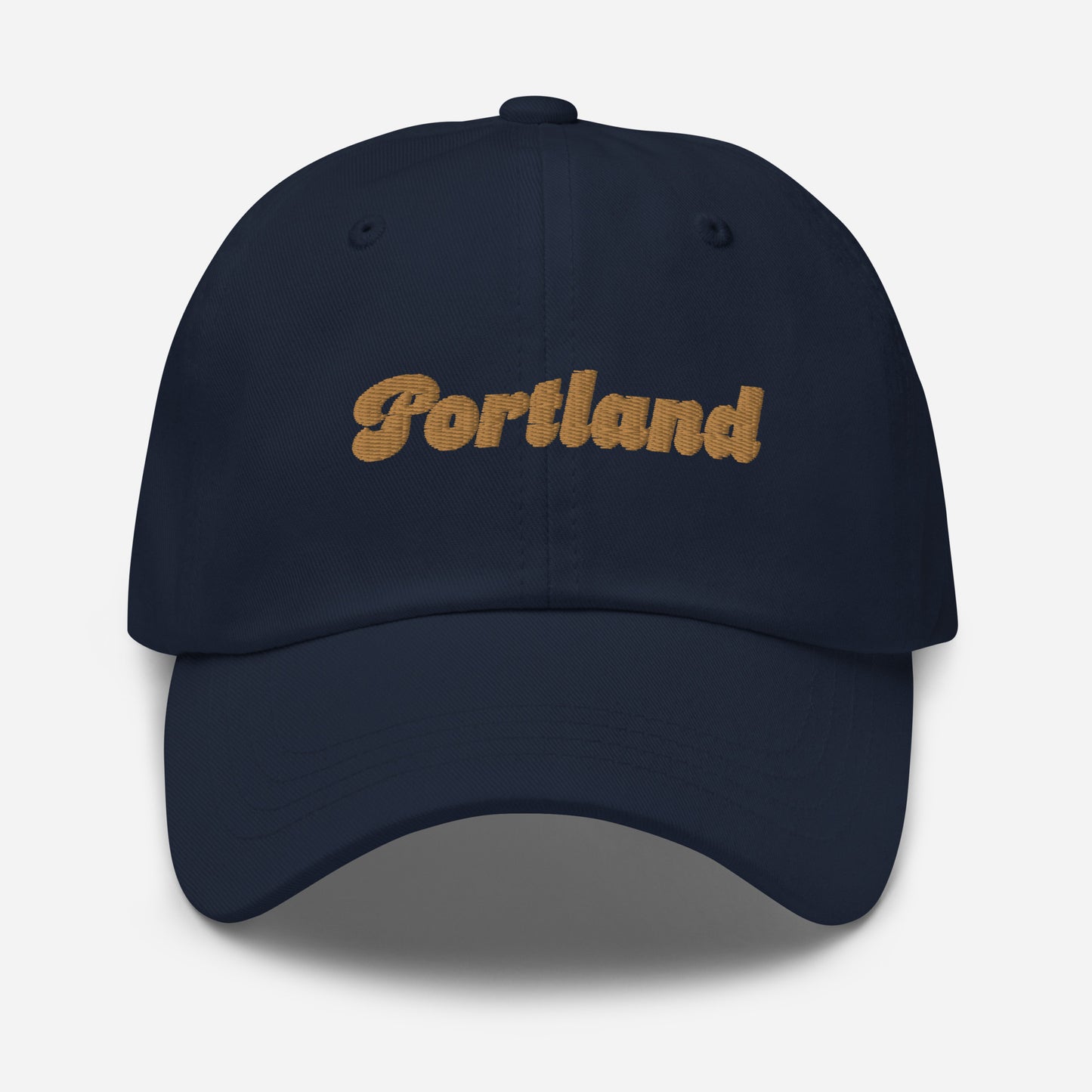 Portland city editions with “Portland” type in gold embroidery on navy casual dad hat front view on white background