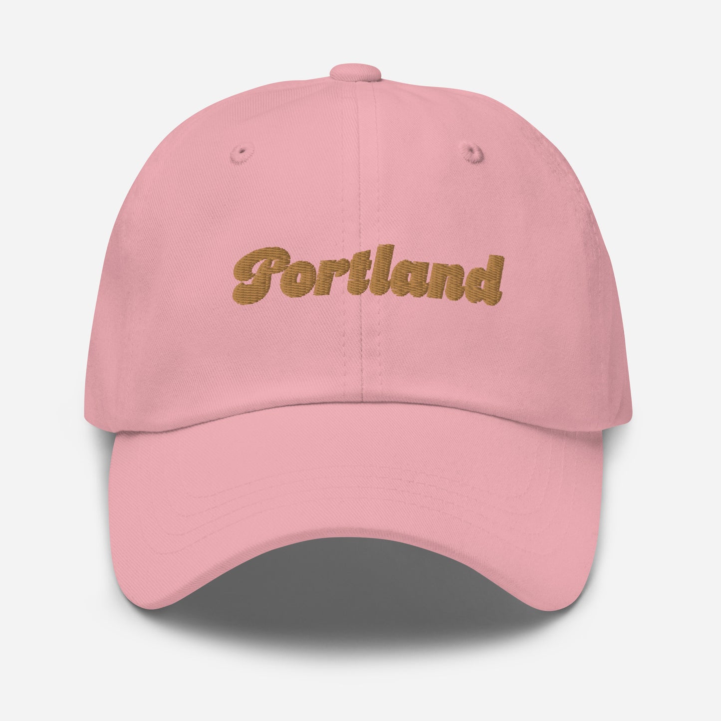 Portland city editions with “Portland” type in gold embroidery on pink casual dad hat front view on white background
