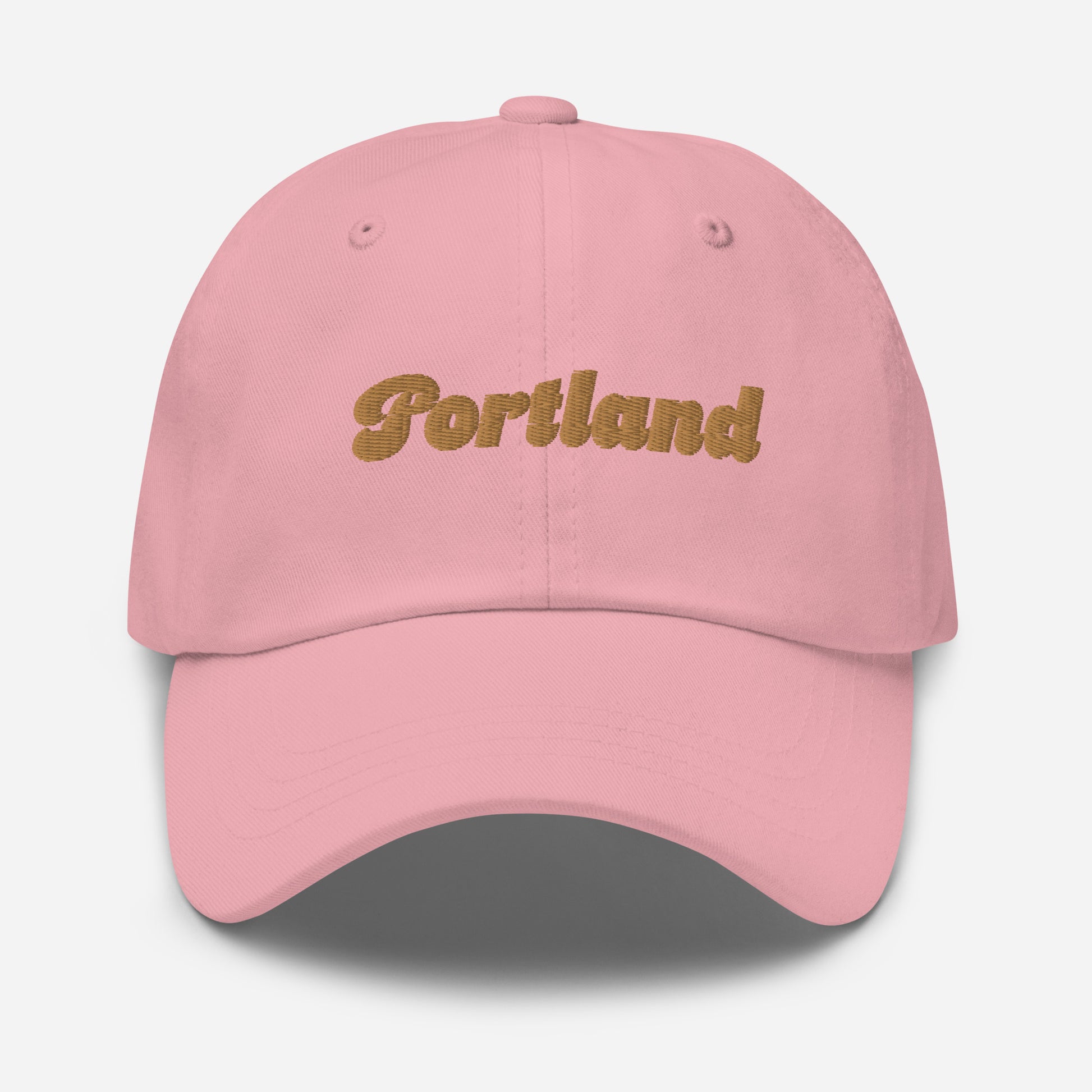Portland city editions with “Portland” type in gold embroidery on pink casual dad hat front view on white background