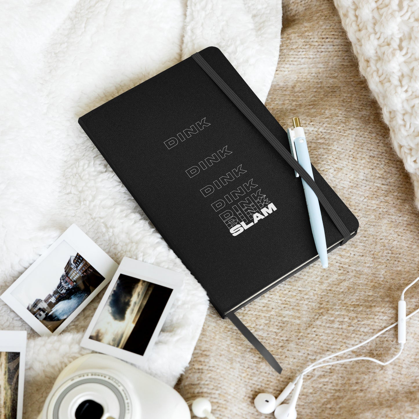 Dink Dink Slam type on black notebook, front view on layered fabric background