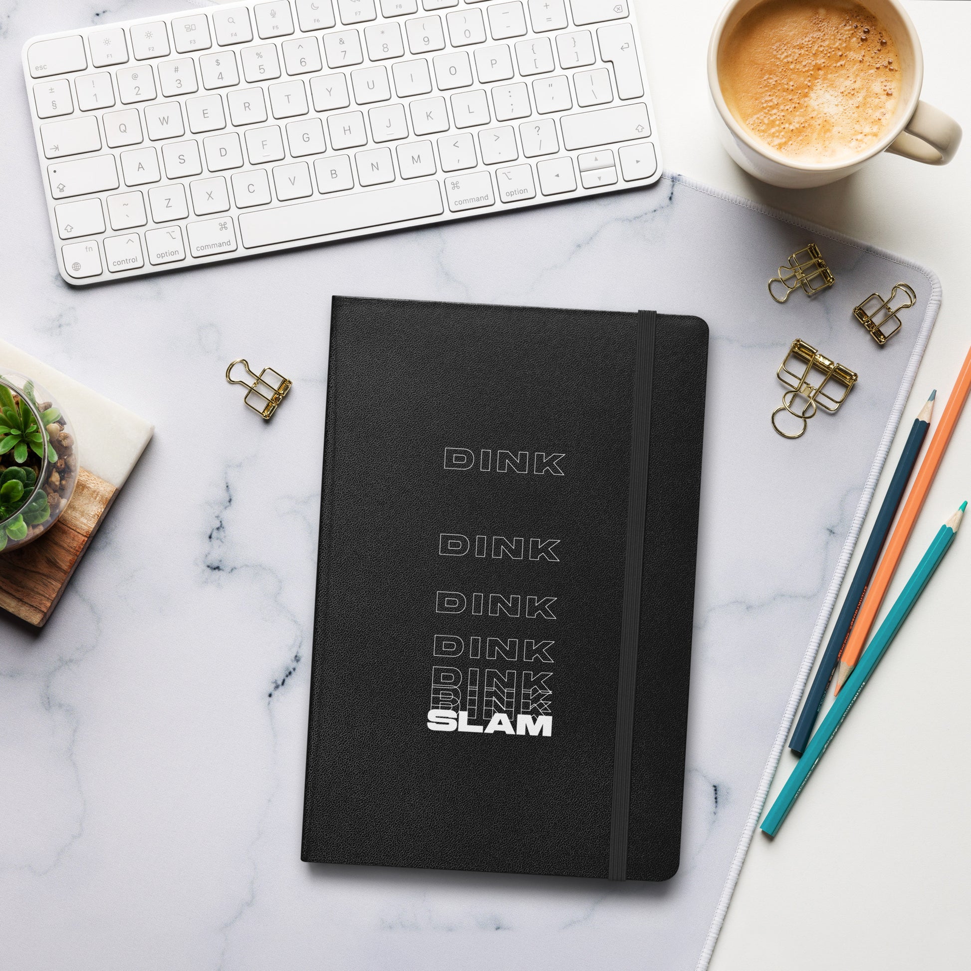 Dink Dink Slam type on black notebook, front view on marble surface with work accessories