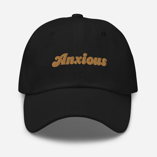 Portland city editions with “Anxious” type in gold embroidery on black casual dad hat front view on white background