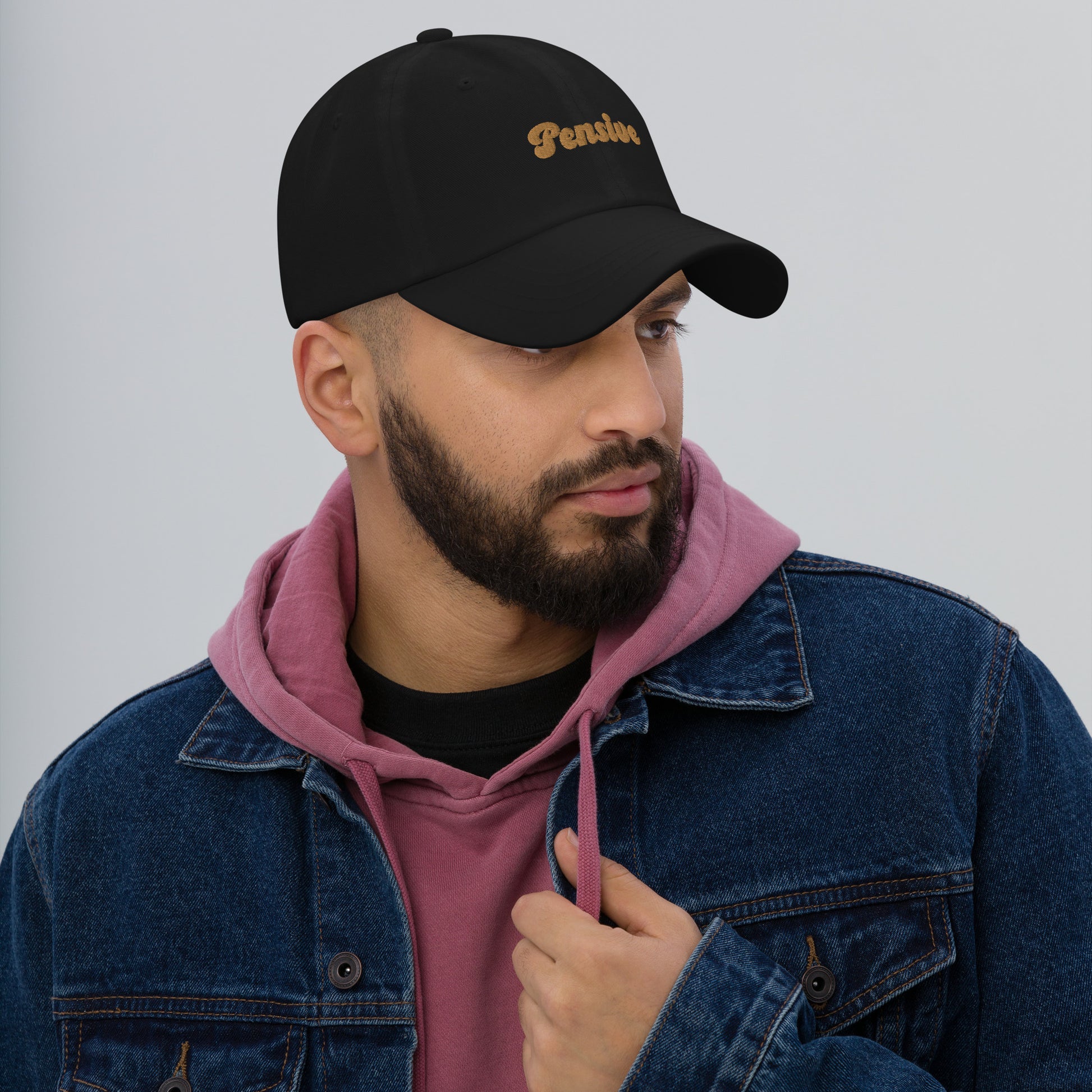 Portland city editions with “Pensive” type in gold embroidery on black casual dad hat front view on male model