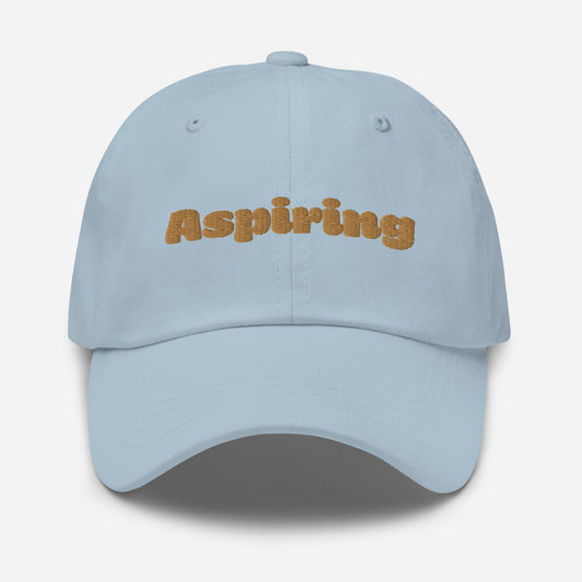 Los Angeles city editions with “Aspiring” type in gold embroidery on light blue casual dad hat front view on white background