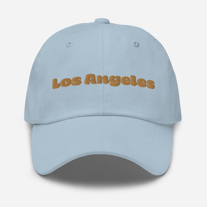 Los Angeles city editions with “Los Angeles” type in gold embroidery on light blue casual dad hat front view on white background