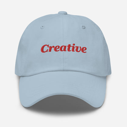 London city editions with “Creative” type in red embroidery on light blue casual dad hat front view on white background