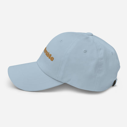 Los Angeles city editions with “Insufferable” type in gold embroidery on light blue casual dad hat side view on white background