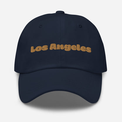 Los Angeles city editions with “Los Angeles” type in gold embroidery on navy casual dad hat front view on white background