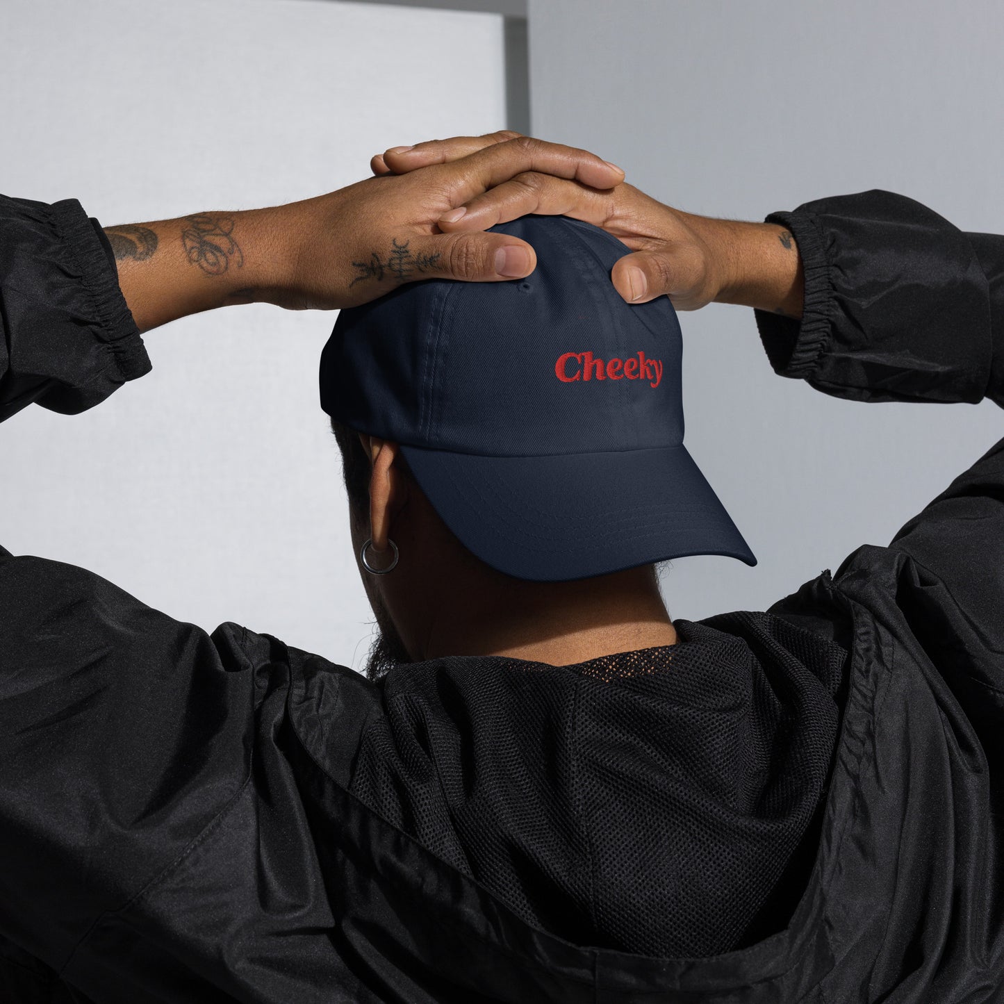 London city editions with “Cheeky” type in red embroidery on navy casual dad hat front view on male model