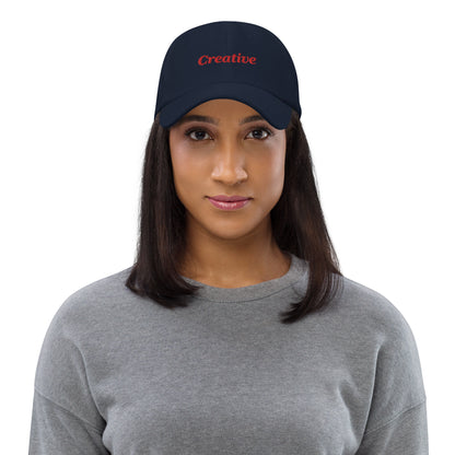 London city editions with “Creative” type in red embroidery on navy casual dad hat front view on female model