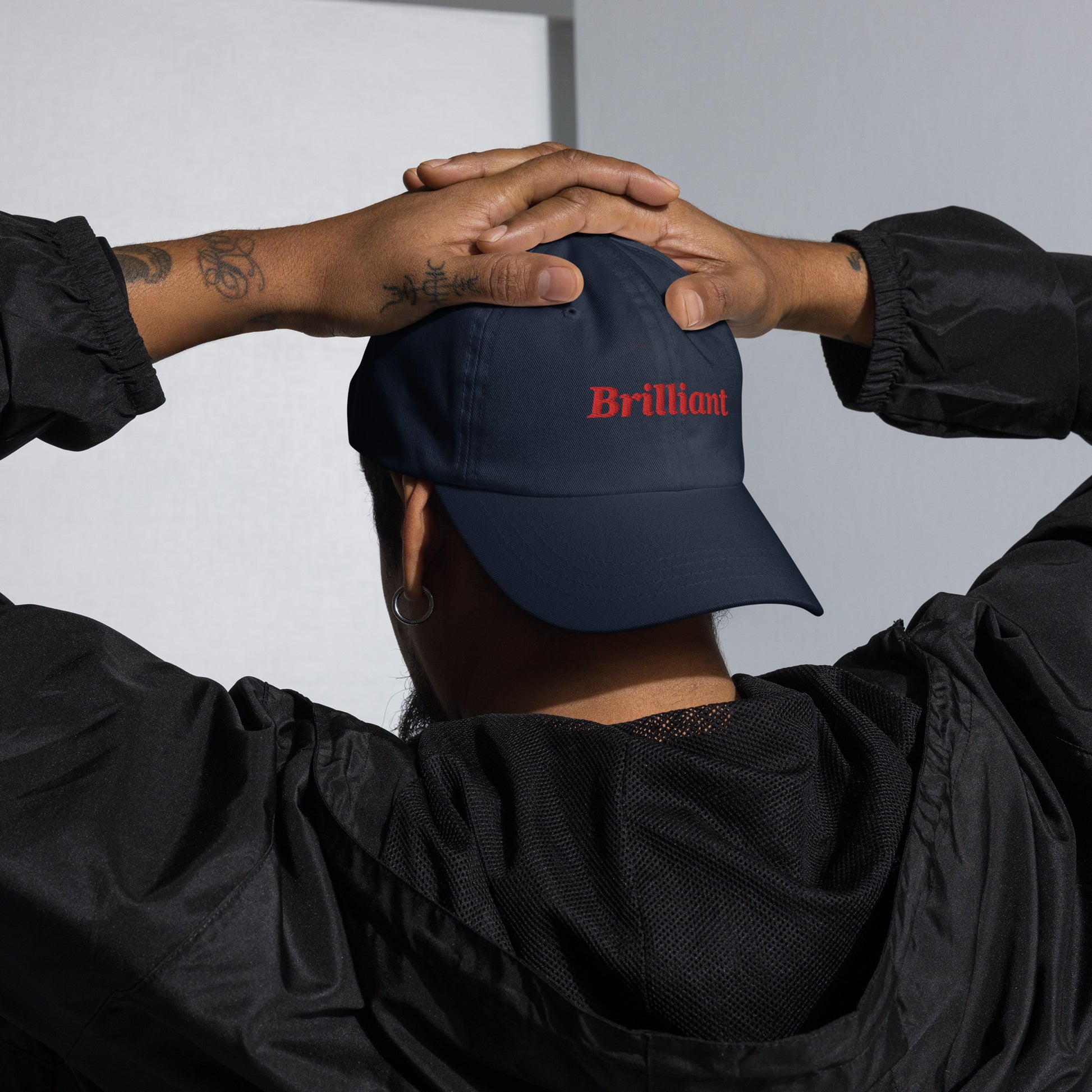 London city editions with “Brilliant” type in red embroidery on navy casual dad hat front view on male model