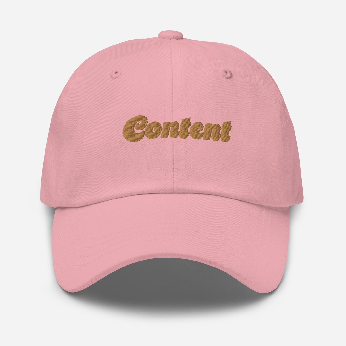 Portland city editions with “Content” type in gold embroidery on pink casual dad hat front view on white background