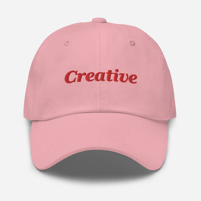 London city editions with “Creative” type in red embroidery on pink casual dad hat front view on white background