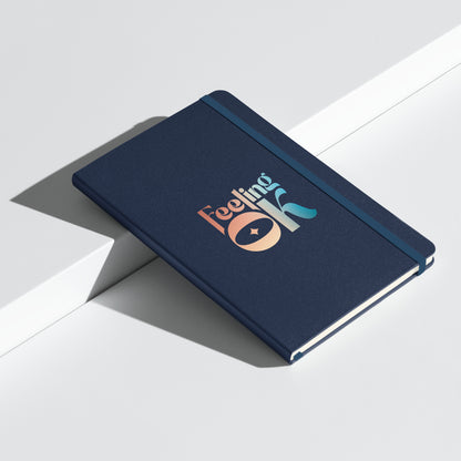 Feeling OK type on navy blue notebook, front angled view on white background